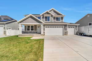 Craftsman house with board and batten siding, stone siding, a porch, and a front yard