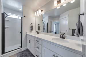 Bathroom featuring double vanity, a shower stall, and a sink
