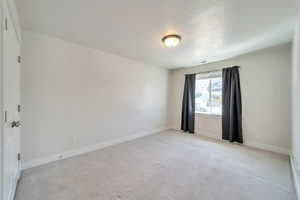 Unfurnished room featuring visible vents, baseboards, and light carpet