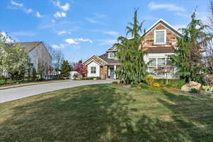 View of front of house featuring stone siding, a front lawn, and concrete driveway