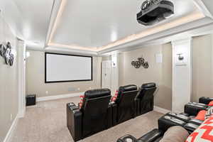 Carpeted cinema room featuring baseboards and a raised ceiling