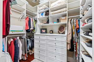 Spacious closet with dark wood-type flooring and visible vents