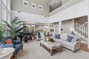Living room featuring a towering ceiling, stairs, and decorative columns