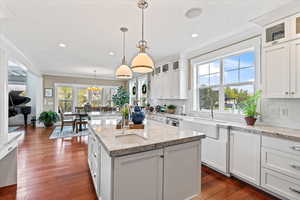 Kitchen with decorative backsplash, crown molding, a sink, and a kitchen island with sink