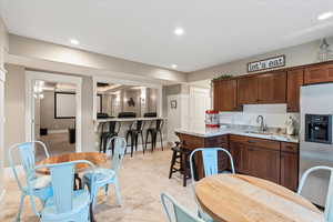 Kitchen with a sink, stainless steel fridge, baseboards, recessed lighting, and light stone countertops