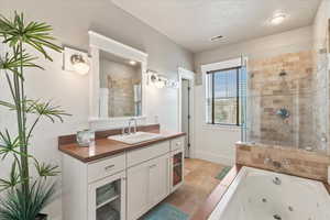 Bathroom with visible vents, vanity, a tub with jets, baseboards, and a stall shower
