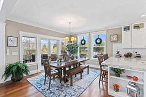 Dining space featuring visible vents, crown molding, baseboards, hardwood / wood-style flooring, and a notable chandelier