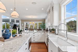 Kitchen with a peninsula, a sink, stainless steel microwave, dark wood-style flooring, and a chandelier