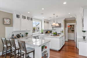 Kitchen featuring decorative backsplash, a peninsula, white cabinetry, and a center island with sink
