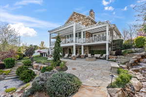 Rear view of property with a fire pit, stone siding, a chimney, stairway, and a patio