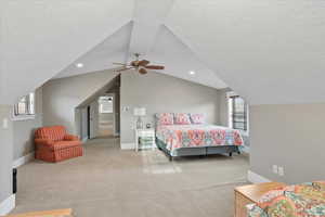 Carpeted bedroom with lofted ceiling, a textured ceiling, and baseboards