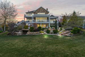 Back of property at dusk with a pergola, a yard, and a patio