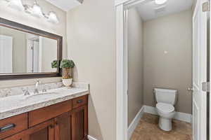 Bathroom featuring baseboards, visible vents, vanity, and toilet