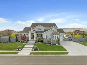 Craftsman inspired home featuring concrete driveway, a front lawn, fence, and stone siding