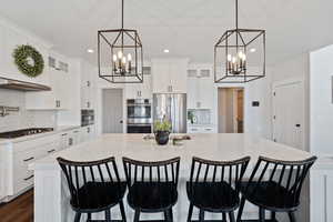 Kitchen with stainless steel appliances, a chandelier, tasteful backsplash, and a spacious island