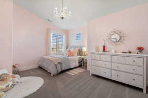Bedroom featuring a chandelier, vaulted ceiling, baseboards, and carpet