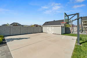 View of patio with a fenced backyard, an outdoor structure, and basketball hoop