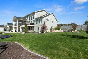 Rear view of property with fence, a lawn, a balcony, and a patio