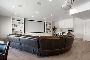 Carpeted home theater featuring a textured ceiling, a sink, visible vents, recessed lighting, and beverage cooler