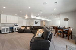 Living area featuring indoor wet bar, beverage cooler, recessed lighting, and light colored carpet