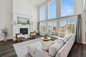 Living room featuring baseboards, a towering ceiling, and dark wood-type flooring