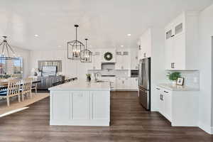 Kitchen with a kitchen island with sink, freestanding refrigerator, an inviting chandelier, recessed lighting, and light countertops
