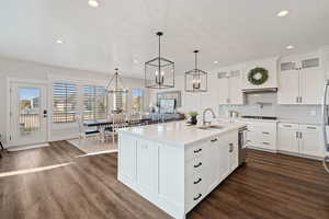 Kitchen featuring recessed lighting, an inviting chandelier, light countertops, a sink, and dark wood-type flooring