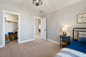 Carpeted bedroom with lofted ceiling, baseboards, and visible vents