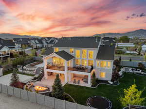 Back of property at dusk with stairway, a fenced backyard, a yard, a patio area, and an outdoor fire pit