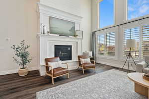 Sitting room featuring baseboards, wood finished floors, a high ceiling, and a fireplace