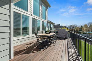 Wooden deck featuring outdoor dining area and a grill