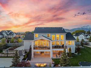 Back of house at dusk with a fenced backyard, a patio, stairs, and an outdoor fire pit