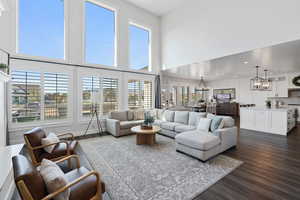 Living area with an inviting chandelier, dark wood-style flooring, a high ceiling, and recessed lighting