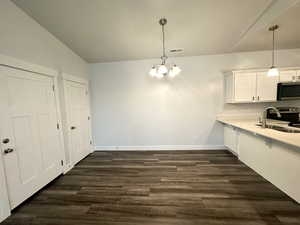 Kitchen featuring stainless steel appliances,  white cabinetry, a sink, and a notable chandelier
