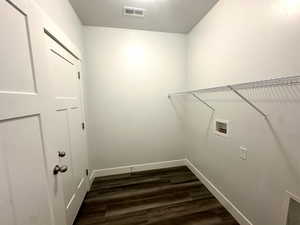 Clothes washing area featuring dark wood-style floors, visible vents, baseboards, washer hookup, and laundry area