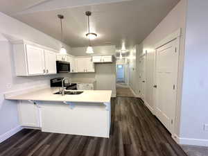 Kitchen with a peninsula, a sink, baseboards, light countertops, and appliances with stainless steel finishes
