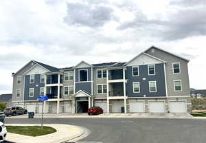 View of front facade featuring board and batten siding, an attached garage, and stone siding