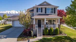 View of front of house featuring roof with shingles, a porch, a front lawn, and concrete driveway