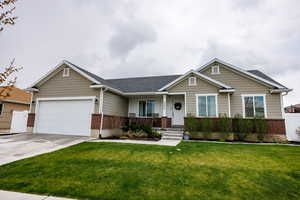 View of front facade with driveway, a porch, a garage, brick siding, and a front yard