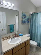 Bathroom featuring a shower with curtain, vanity, tile patterned flooring, and toilet