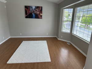 Unfurnished room with baseboards, wood finished floors, and visible vents