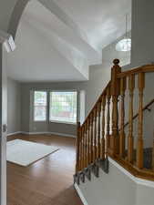 Stairway featuring arched walkways, wood finished floors, and baseboards
