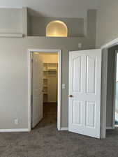 Unfurnished bedroom with baseboards, carpet flooring, a spacious closet, and a closet