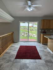 Interior space with stone finish floor, vaulted ceiling, baseboards, and ceiling fan