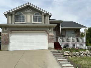 View of front of property with brick siding, covered porch, driveway, and a garage