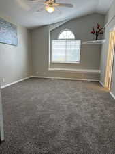 Carpeted empty room featuring attic access, lofted ceiling, a ceiling fan, and baseboards