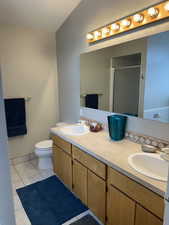 Bathroom featuring double vanity, toilet, a stall shower, and a sink