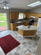 Kitchen with a sink, appliances with stainless steel finishes, light countertops, backsplash, and under cabinet range hood
