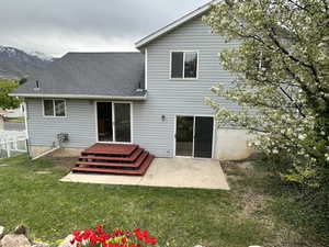 Rear view of house featuring roof with shingles, a mountain view, fence, a patio area, and a yard