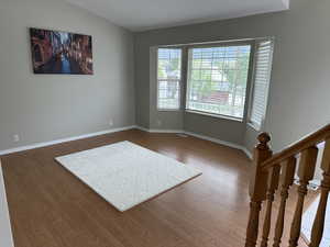 Unfurnished room with baseboards, lofted ceiling, and wood finished floors